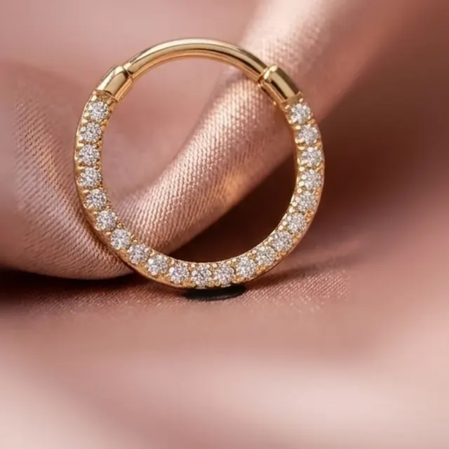 Argola dourada cravejada de cristais sobre cetim rosé